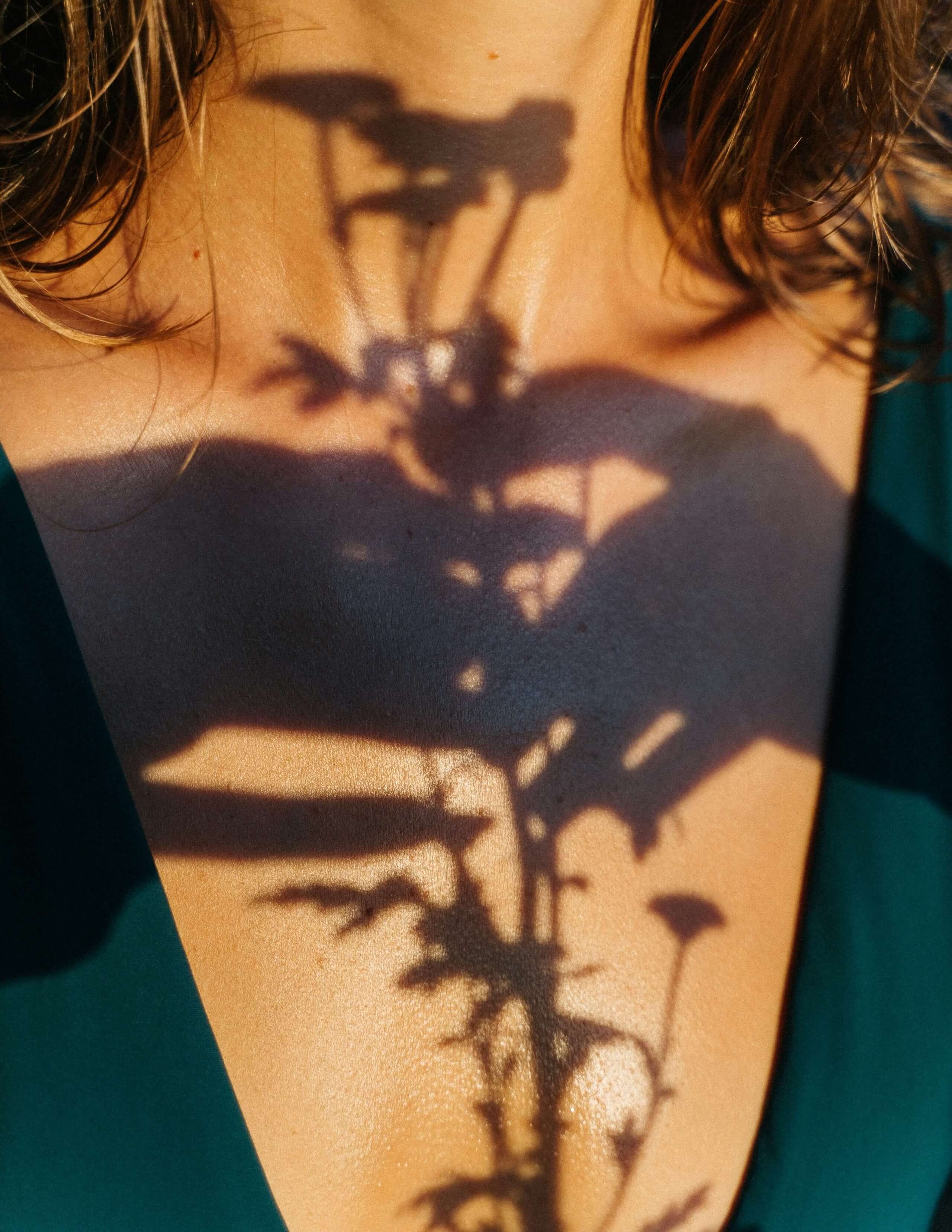 Eine Blume wirft Schatten auf die Brust einer Frau